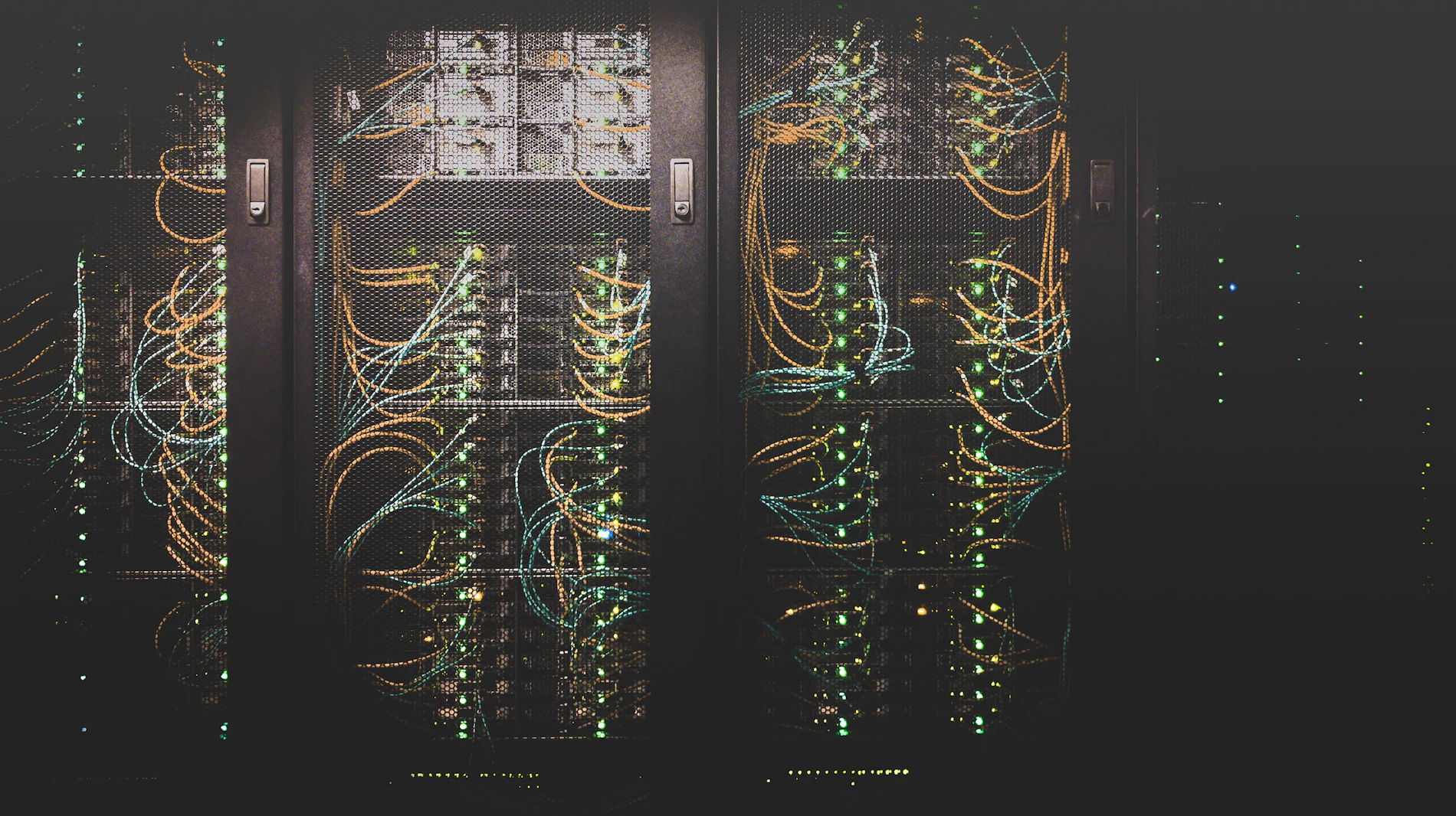 Rows of network equipment in a data centre corridor lit in low light